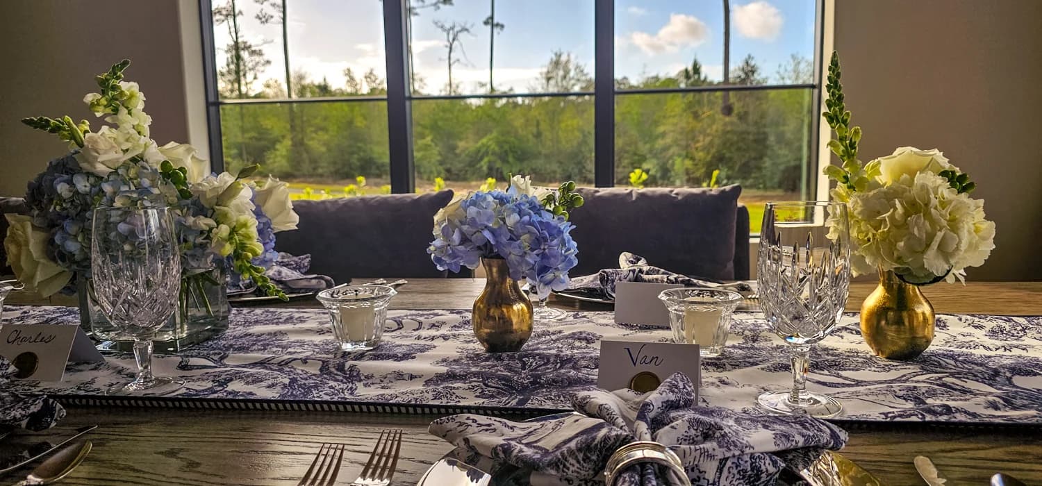 A table set for a private tasting evening — hydrangeas, candlelight, multiple wine glasses placed at each setting